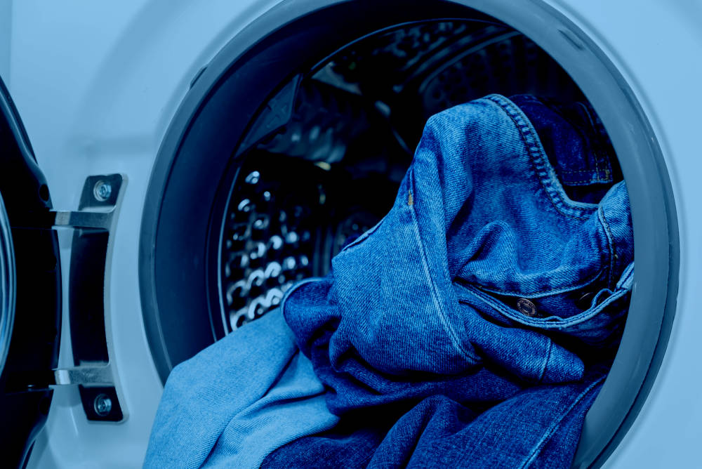 Close-up of a side-loading washing machine with laundry hanging out